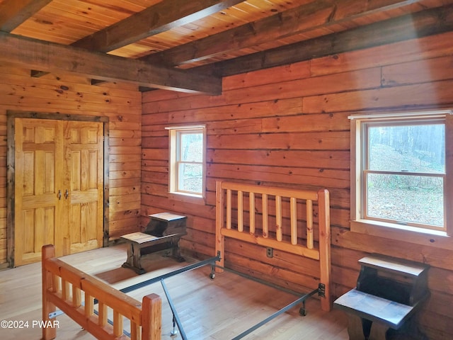 bedroom with wood walls, light hardwood / wood-style flooring, beamed ceiling, and wood ceiling