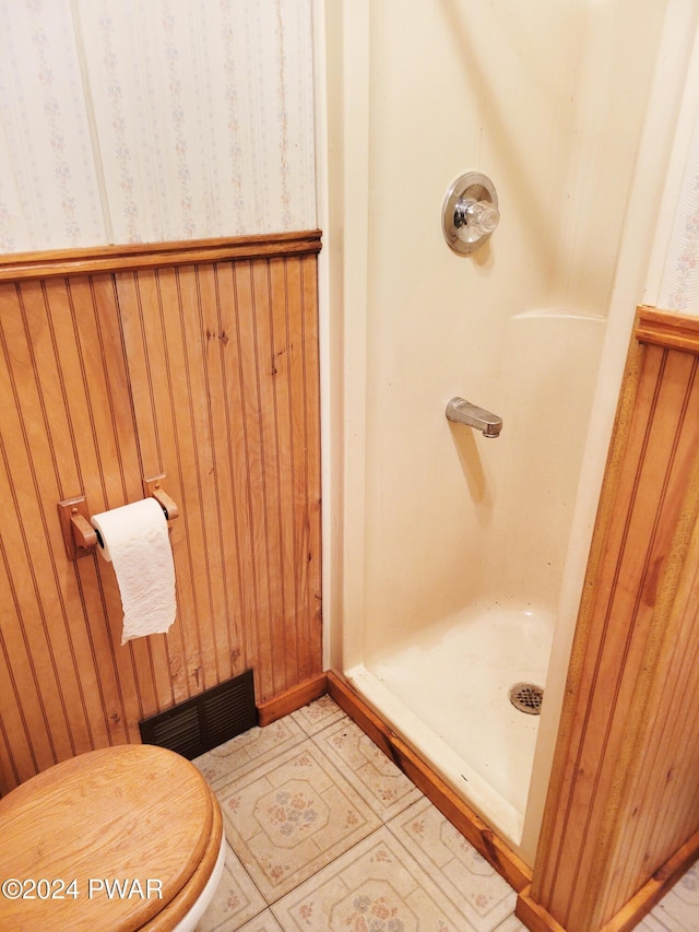 bathroom with wood walls and a shower