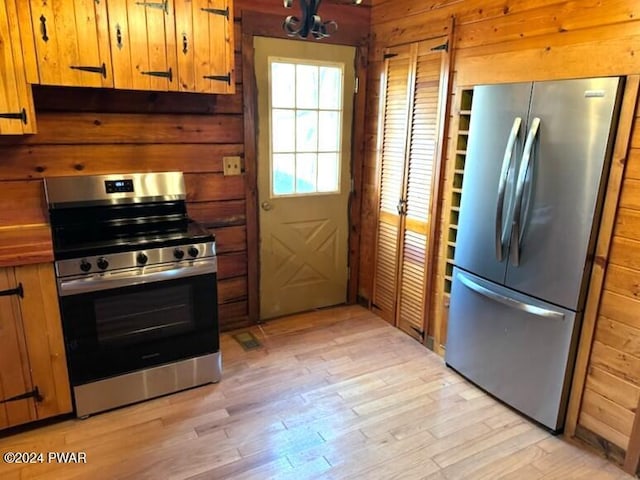 kitchen with stainless steel appliances, light hardwood / wood-style floors, and wood walls