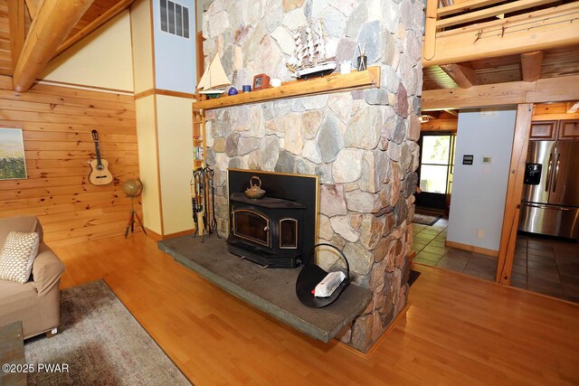 33 Syloro Ln, Damascus, PA 18415 - living room with wood finished floors, beam ceiling, a wood stove, wood walls, and baseboards
