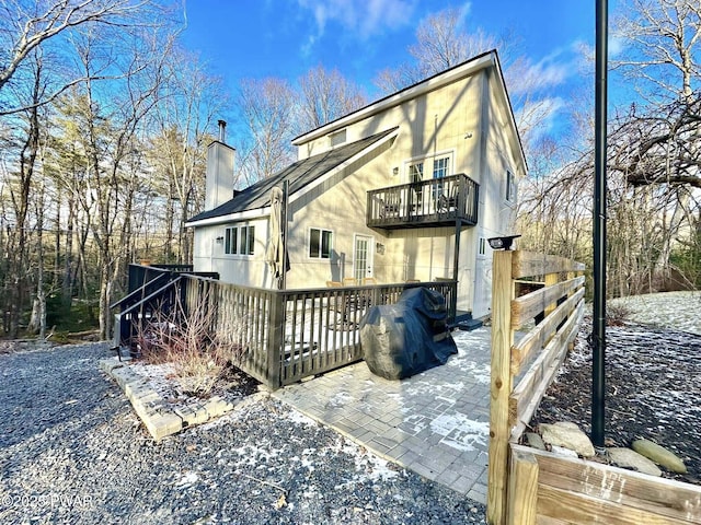 snow covered back of property featuring a balcony and a deck