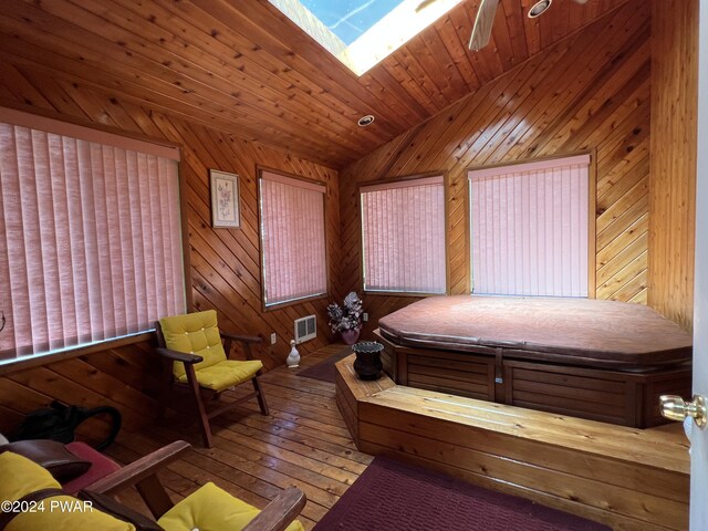 bedroom featuring wood walls, wood-type flooring, lofted ceiling with skylight, and wooden ceiling