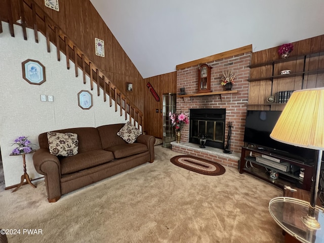 living room featuring wood walls, carpet, lofted ceiling, and a brick fireplace