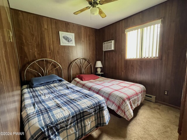 carpeted bedroom featuring ceiling fan, a baseboard heating unit, and wood walls