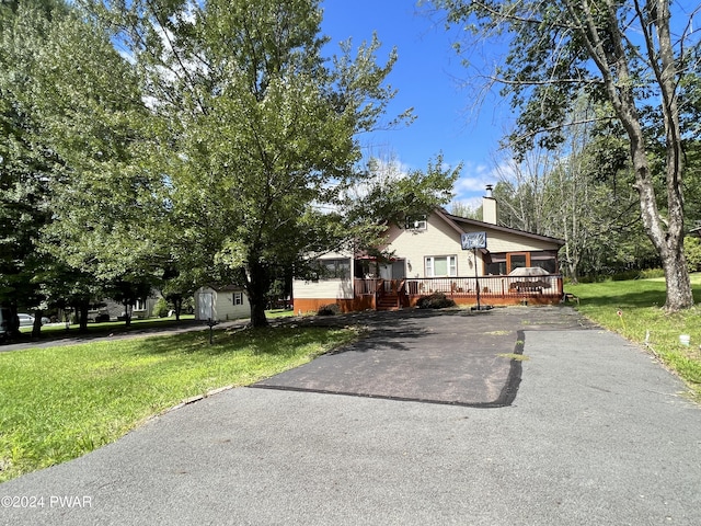 view of front of property with a front yard, a shed, and a wooden deck