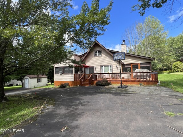 view of front of property featuring a deck and a storage unit