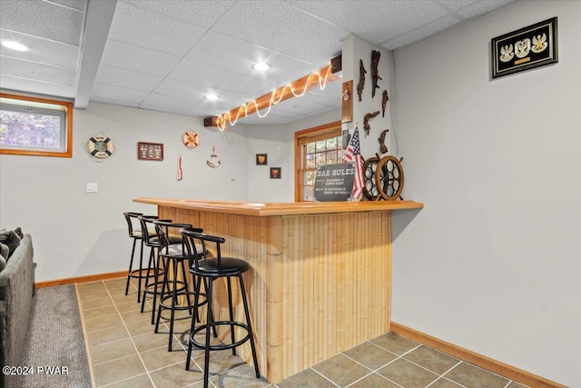 bar featuring tile patterned flooring and a drop ceiling