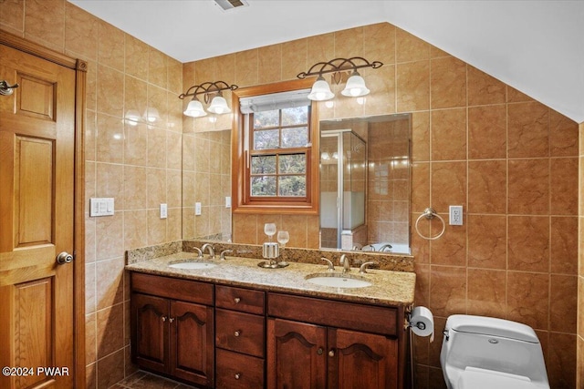 bathroom featuring vanity, toilet, tile walls, and vaulted ceiling