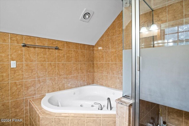 bathroom with vaulted ceiling, tile walls, and independent shower and bath