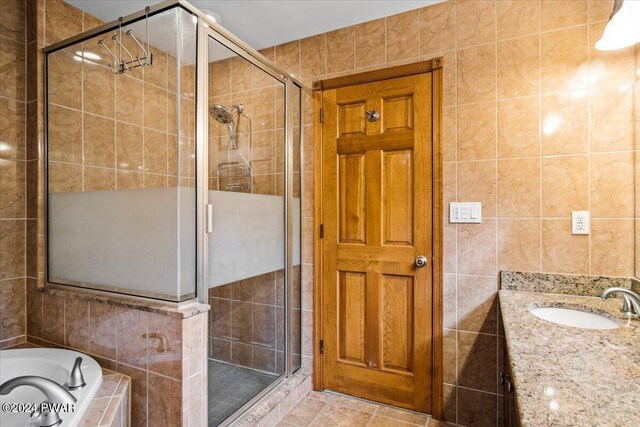 bathroom featuring shower with separate bathtub, vanity, and tile walls