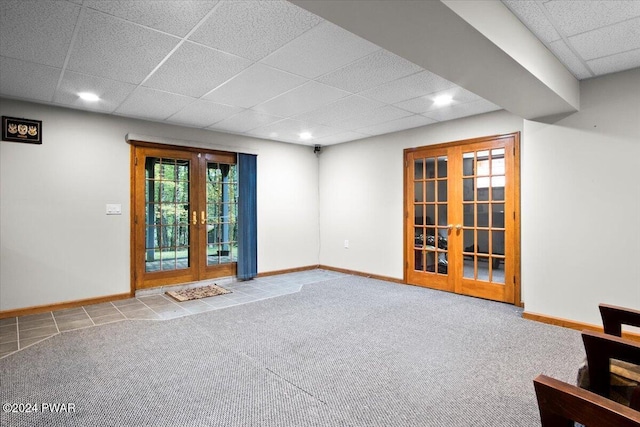 carpeted empty room featuring a drop ceiling and french doors