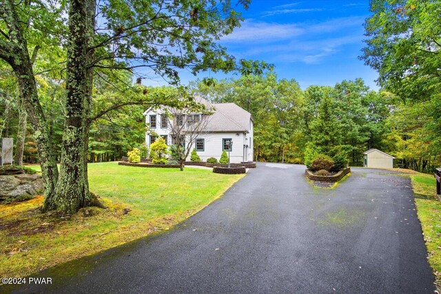 colonial home featuring a front lawn, an outdoor structure, and a garage