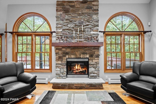 living room featuring a fireplace, wood-type flooring, and a baseboard heating unit