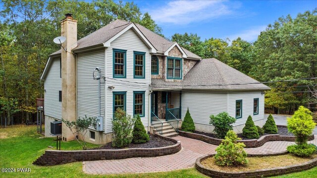 view of front of home with cooling unit and a front lawn