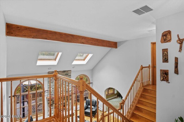 staircase featuring vaulted ceiling with skylight and hardwood / wood-style flooring