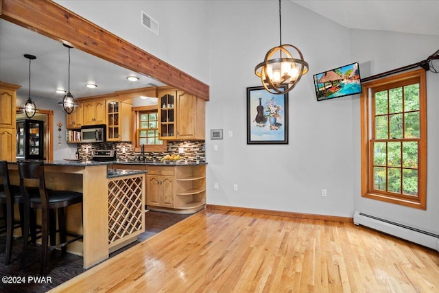 kitchen with pendant lighting, lofted ceiling, a baseboard radiator, and tasteful backsplash