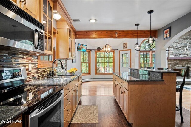 kitchen with decorative backsplash, dark stone counters, stainless steel appliances, sink, and a kitchen island