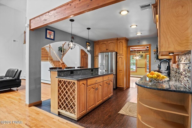 kitchen with stainless steel refrigerator with ice dispenser, dark hardwood / wood-style floors, tasteful backsplash, and pendant lighting