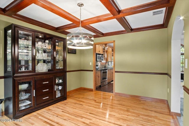 dining area with coffered ceiling, sink, beam ceiling, light hardwood / wood-style flooring, and an inviting chandelier