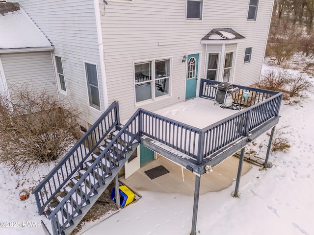 snow covered deck with grilling area and stairs