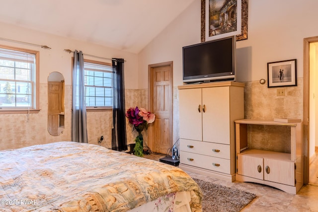 bedroom with wainscoting, multiple windows, and vaulted ceiling