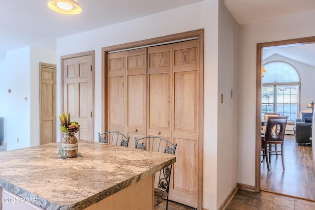 kitchen with a breakfast bar, a center island, light countertops, light brown cabinets, and baseboards