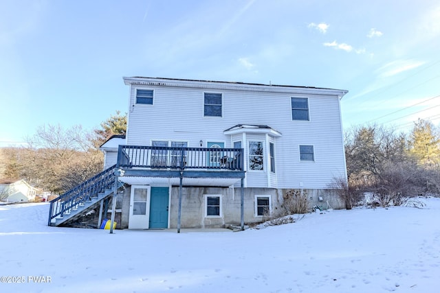 snow covered property featuring a deck and stairs