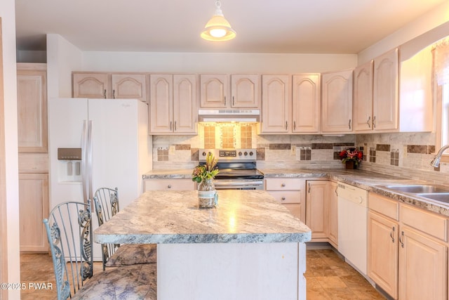 kitchen with white appliances, a sink, under cabinet range hood, and light brown cabinetry