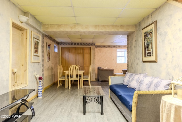 living room featuring wood finished floors, a paneled ceiling, and baseboards