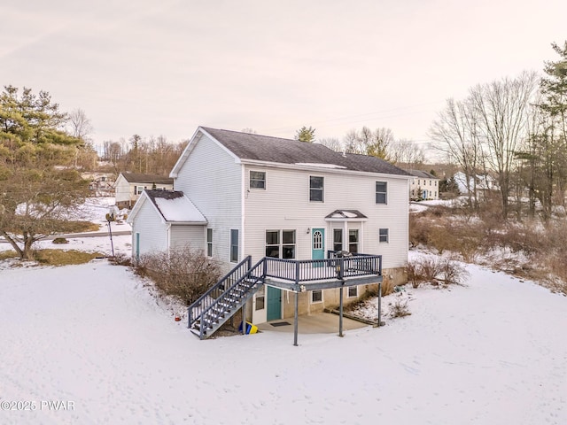 snow covered rear of property featuring a wooden deck and stairs