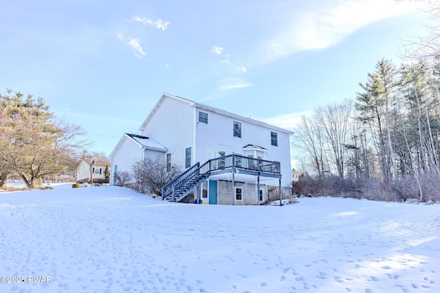 snow covered house with stairway and a wooden deck