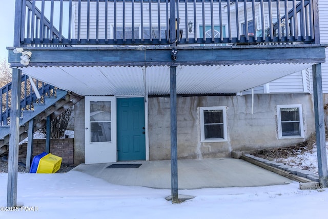 snow covered property entrance with a patio