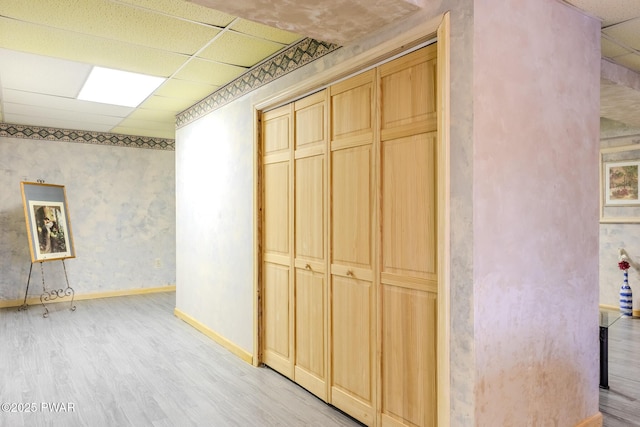 interior space with light wood-type flooring, baseboards, and a drop ceiling