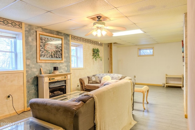 living room with light wood-style floors, a wealth of natural light, and a drop ceiling