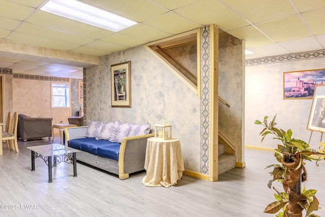 living area featuring a paneled ceiling, stairs, and wood finished floors