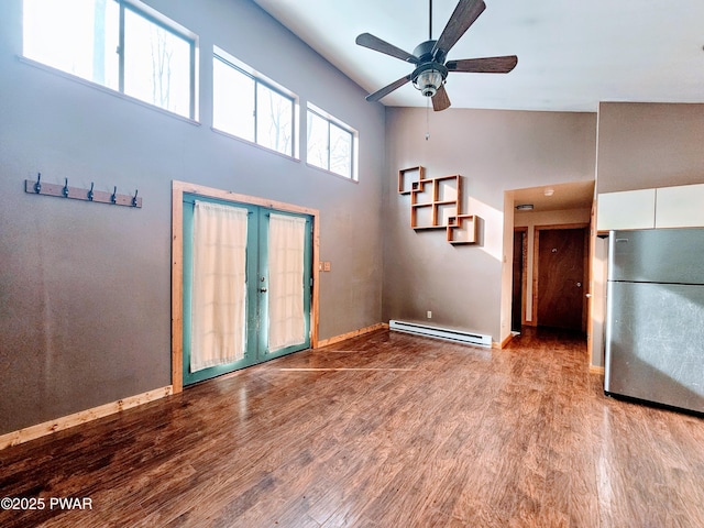 interior space with light hardwood / wood-style flooring, a baseboard radiator, french doors, and a high ceiling