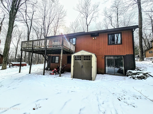 snow covered house with a wooden deck and a shed