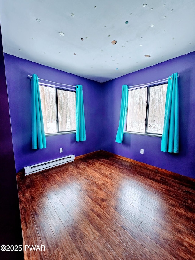 unfurnished room featuring a baseboard heating unit and hardwood / wood-style floors