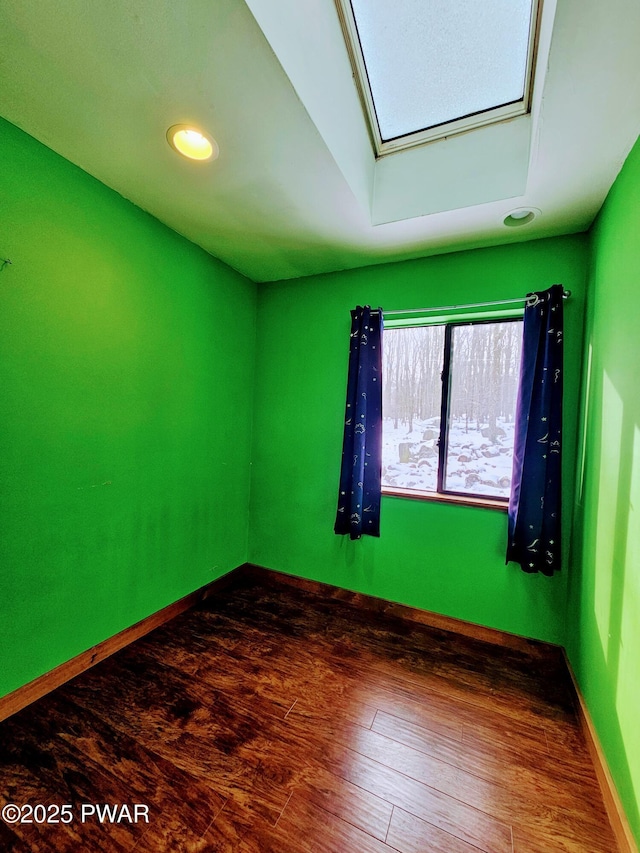 empty room with a skylight and dark wood-type flooring