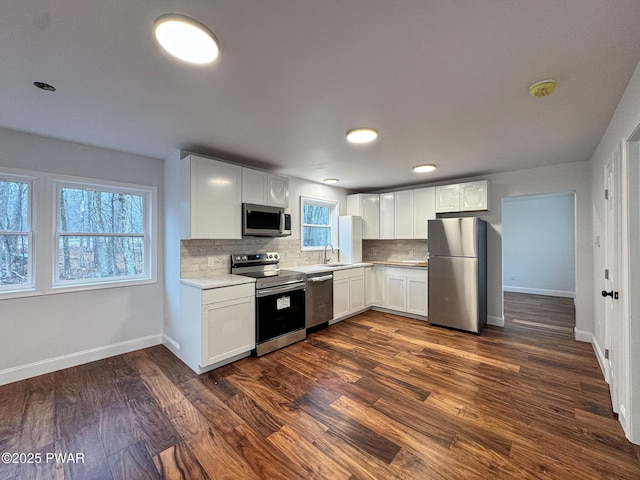kitchen featuring appliances with stainless steel finishes, baseboards, light countertops, decorative backsplash, and white cabinets