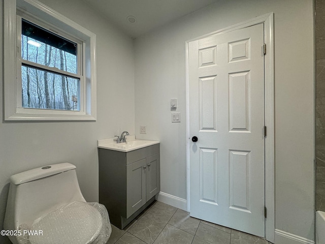 bathroom featuring vanity, toilet, and baseboards