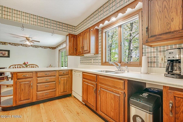 146 Cove Point Cir, Lakeville, PA 18438 - kitchen featuring a sink, white dishwasher, a peninsula, brown cabinetry, and wallpapered walls