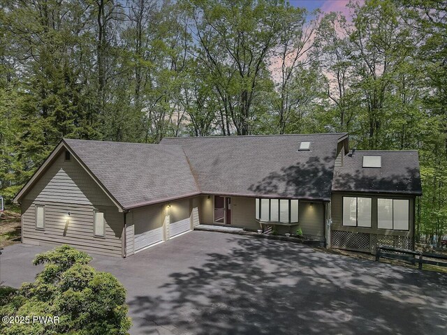 146 Cove Point Cir, Lakeville, PA 18438 - view of front of home featuring asphalt driveway, an attached garage, a shingled roof, and view of wooded area