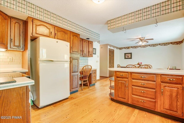 146 Cove Point Cir, Lakeville, PA 18438 - kitchen featuring freestanding refrigerator, brown cabinetry, light wood-style floors, light countertops, and a textured ceiling