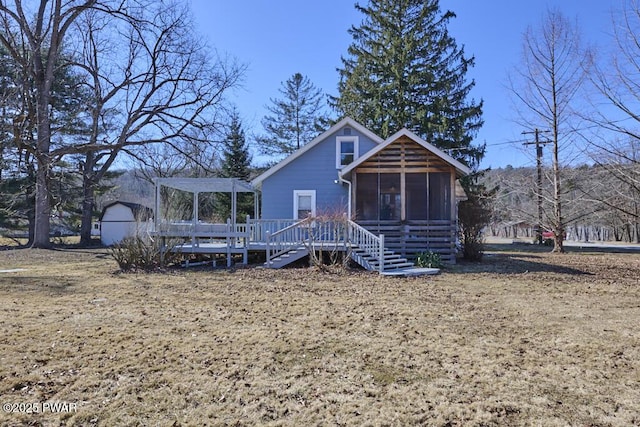 view of front facade with an outbuilding, a wooden deck, a pergola, a sunroom, and stairs