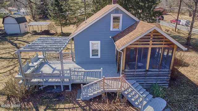 rear view of house featuring an outbuilding, a storage shed, a chimney, and a shingled roof