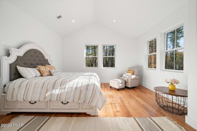 bedroom featuring light hardwood / wood-style floors, multiple windows, and lofted ceiling