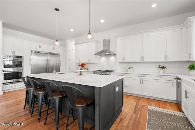 kitchen with white cabinets, a kitchen island with sink, and wall chimney exhaust hood