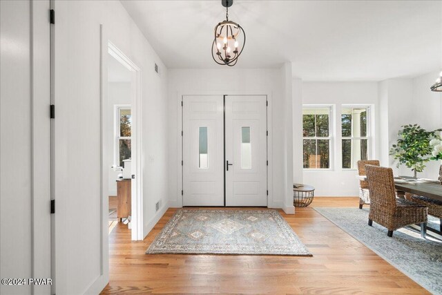 foyer entrance with a chandelier and light wood-type flooring