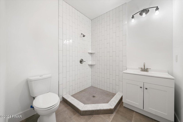 bathroom with tile patterned flooring, vanity, toilet, and tiled shower